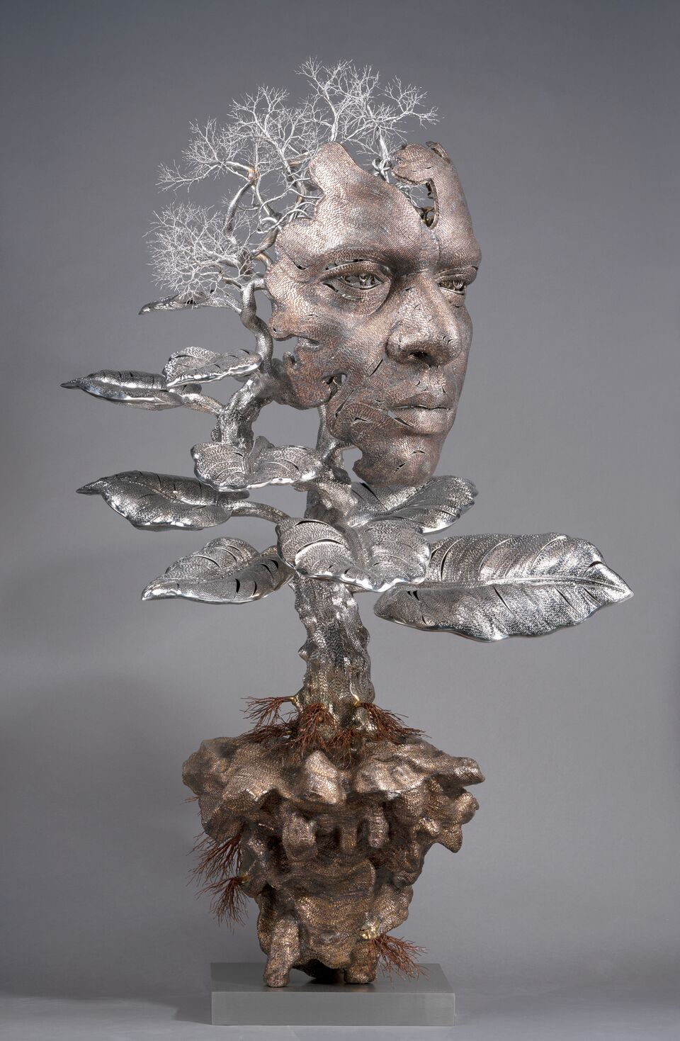 I Am Within You (2020) by Dhananjay Singh: a copper-toned wire face merging into a stainless steel tree with broad leaves, above a copper wire root mass